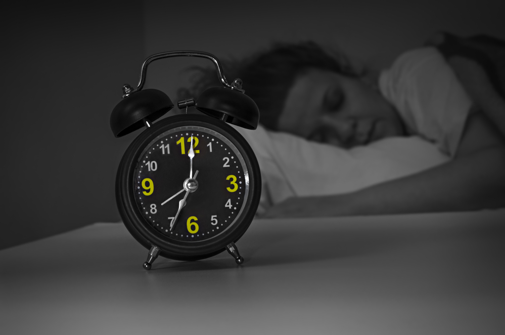 Focus on the alarm clock in front of sleeping woman at night in